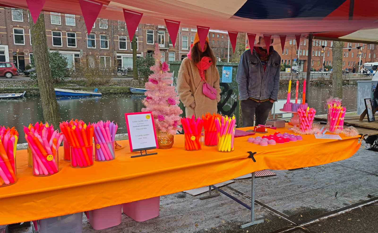 A market stall selling very bright pink and orange candles.