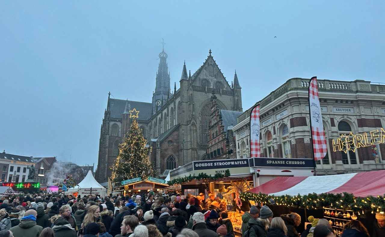A crowded Christmas market in front of a cathedral on a foggy day.